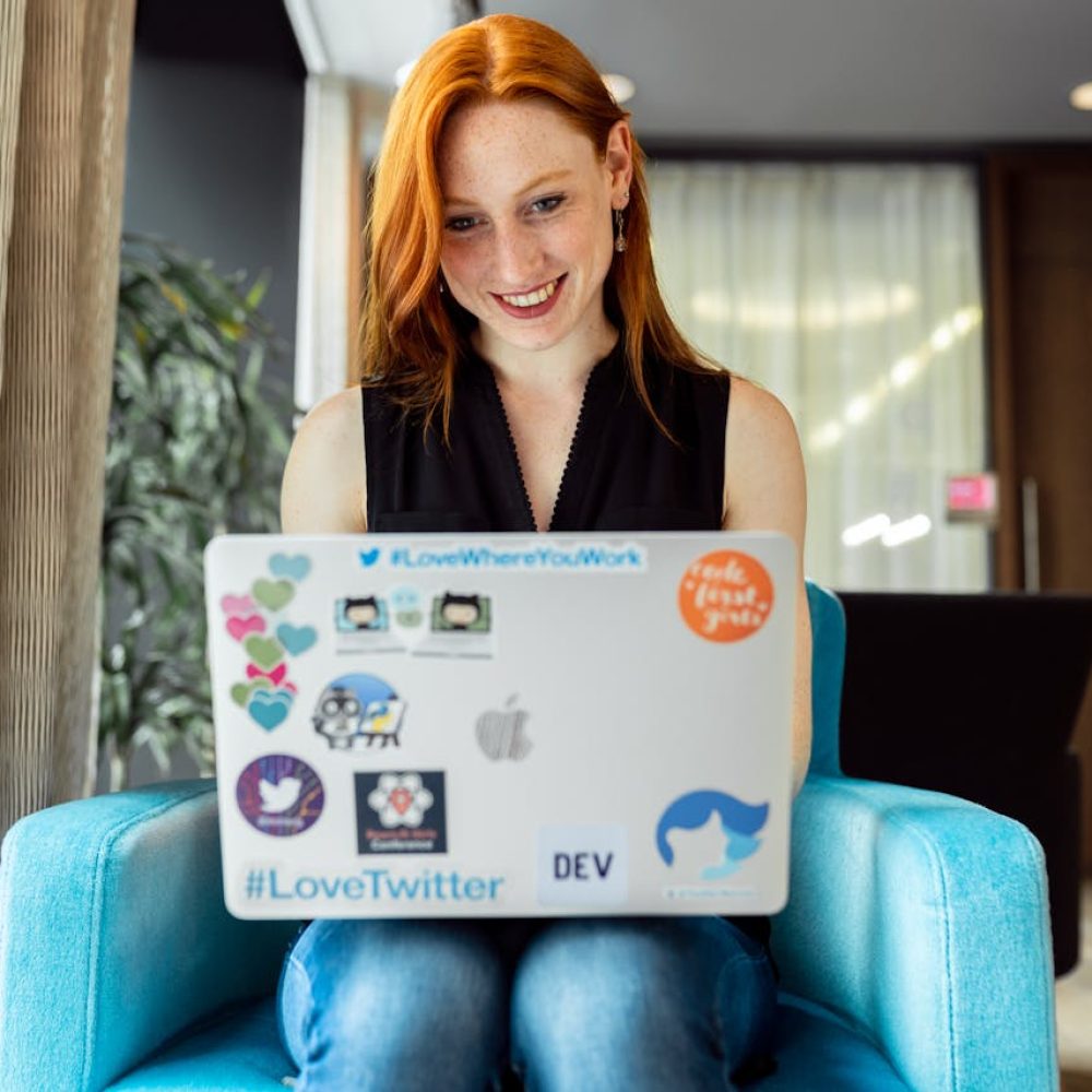 Smiling woman engaged in remote work on a laptop at home office setting.